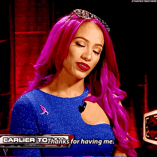 a woman with pink hair is wearing a blue dress and a tiara and says `` earlier to thanks for having me '' .