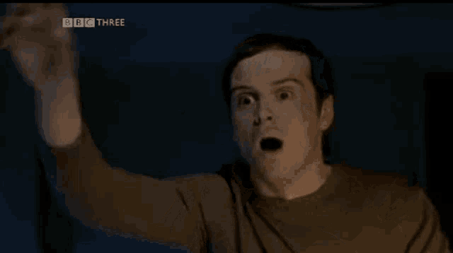 a man with a surprised look on his face is holding a remote control .