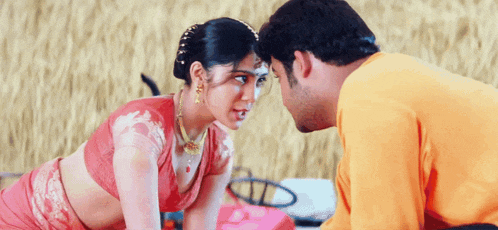 a man and a woman are looking at each other and the man is wearing an orange shirt