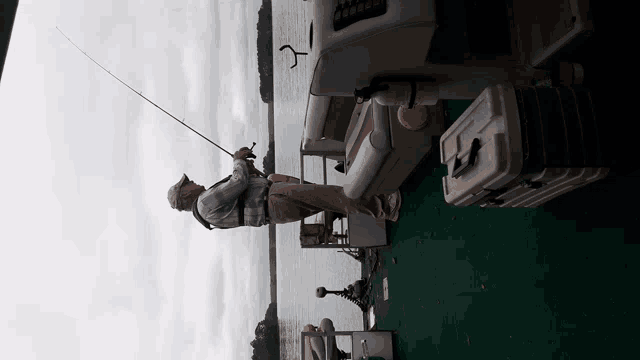 a man is fishing on a boat with a cooler on the deck