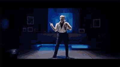 a man in a suit and suspenders is dancing on a stage .