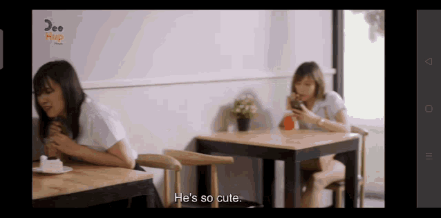 a woman sits at a table with the words he 's so cute
