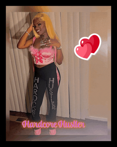 a woman in a pink top and black pants with hardcore hustler on them