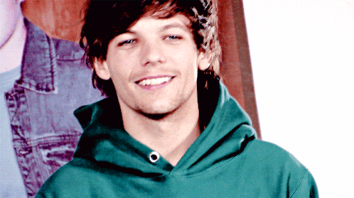 a young man wearing a green hoodie is smiling for the camera