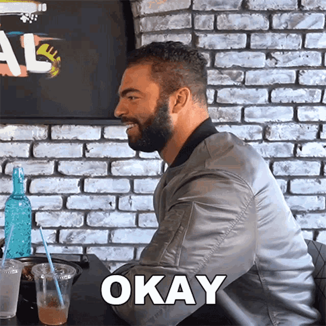 a man with a beard is sitting at a table with okay written on the table