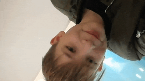 a young boy is looking up at the camera while wearing a black jacket .