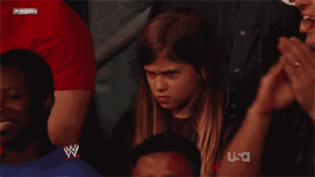 a young girl sitting in a wrestling ring with a w logo on her shirt
