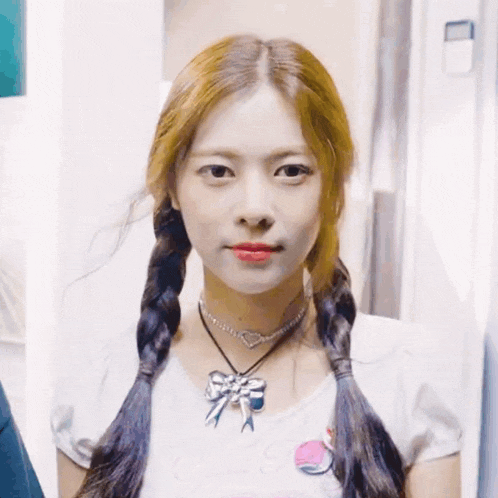 a girl with pigtails wearing a necklace with a bow