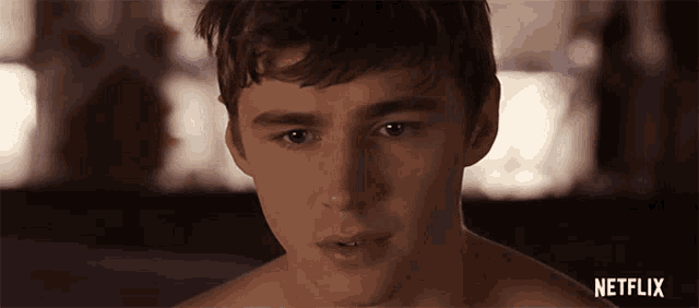 a close up of a shirtless young man 's face with a netflix logo in the corner .