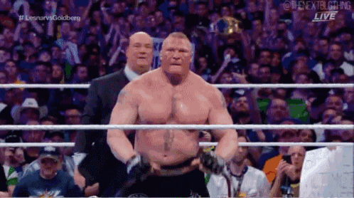 a man is standing in a wrestling ring in front of a crowd while a referee watches .