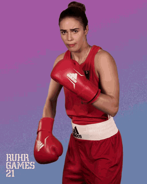 a woman wearing red adidas boxing gloves and red shorts
