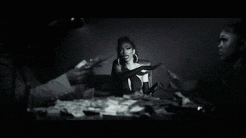 a black and white photo of a woman laying on a bed with money falling around her .