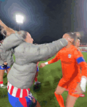 a soccer player in an orange jersey is being tackled by a man in a grey jacket