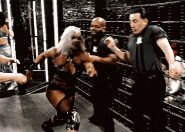 a woman in a black outfit is being held by a man in a black shirt in a wrestling ring .