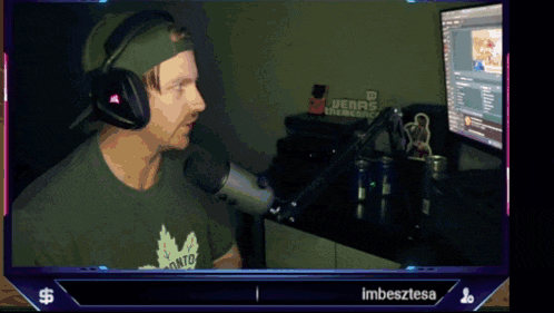 a man wearing headphones and a toronto shirt is talking into a microphone in front of a computer screen