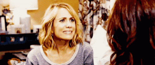 a woman with blonde hair is smiling while talking to another woman with red hair .