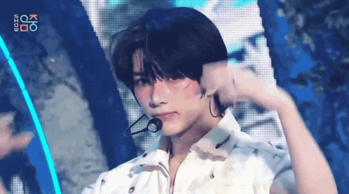 a young man wearing a white shirt and a microphone on a stage