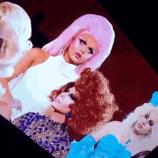 a group of drag queens are standing next to each other in a room .