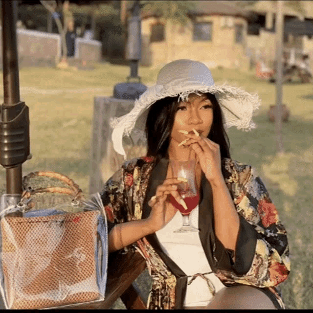 a woman wearing a white hat is drinking from a glass with a straw