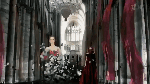 a woman in a red dress is walking down a hallway in a church .