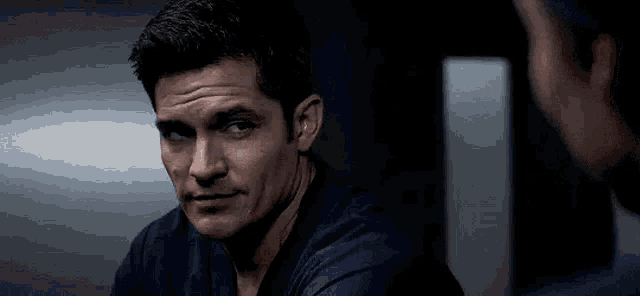 a man in a blue shirt is looking at another man .