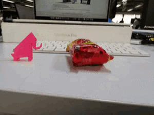 a macbook pro sits on a desk next to a pink origami elephant