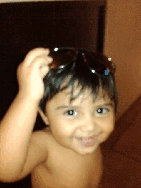 a little boy wearing sunglasses on his head looks at the camera
