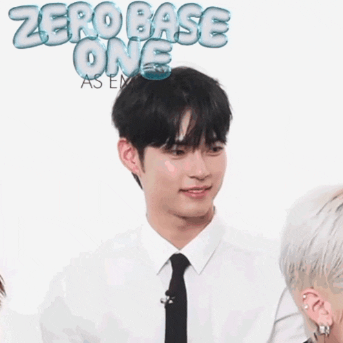 a man in a white shirt and black tie stands in front of a sign that says zero base one as ea