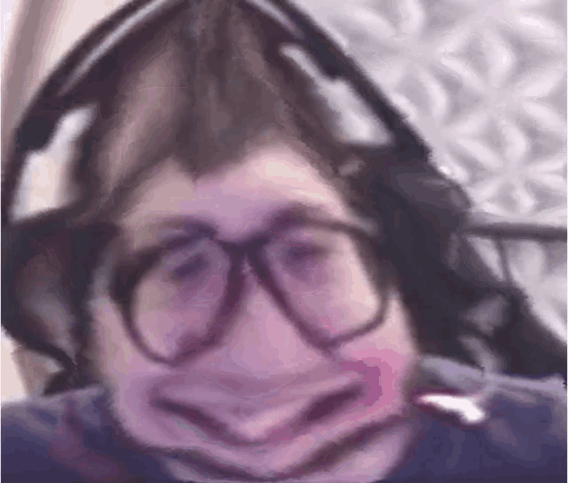 a close up of a person wearing glasses and headphones making a funny face .