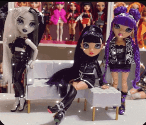 three dolls are sitting on a white couch and one has a jacket that says ' i 'm a princess '