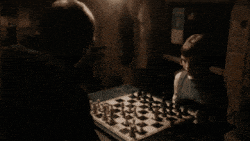 a man and a boy are playing chess in the dark