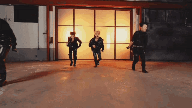 a group of young men are dancing in a dark room
