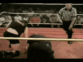a referee stands in a boxing ring watching a wrestler