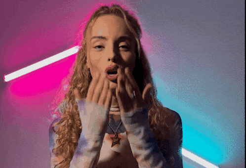 a woman with curly hair is blowing a kiss with her hands