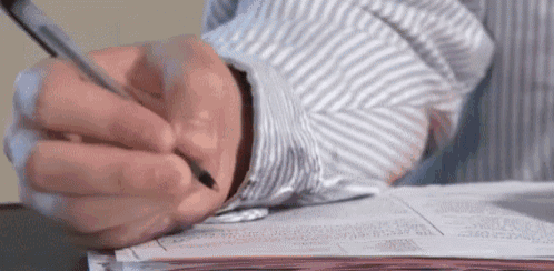 a person is writing on a piece of paper while wearing a striped shirt .