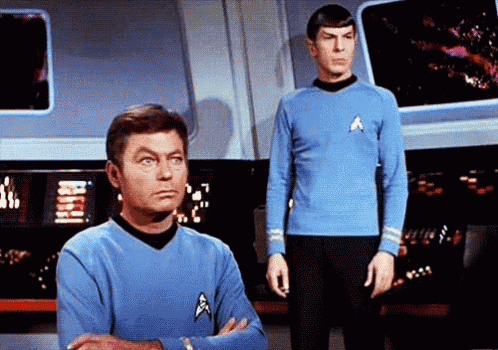 two men in blue shirts are standing next to each other on a stage .