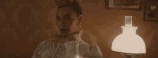 a woman in a white dress is standing in front of a lamp in a dark room .