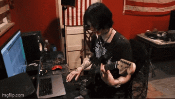 a person is playing a guitar in front of a laptop computer