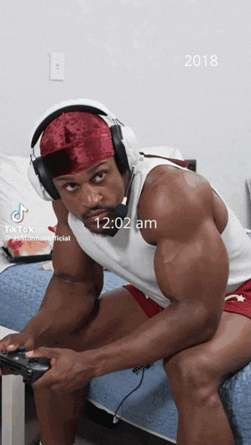 a man wearing headphones and a headband is playing a video game at 12:02 am