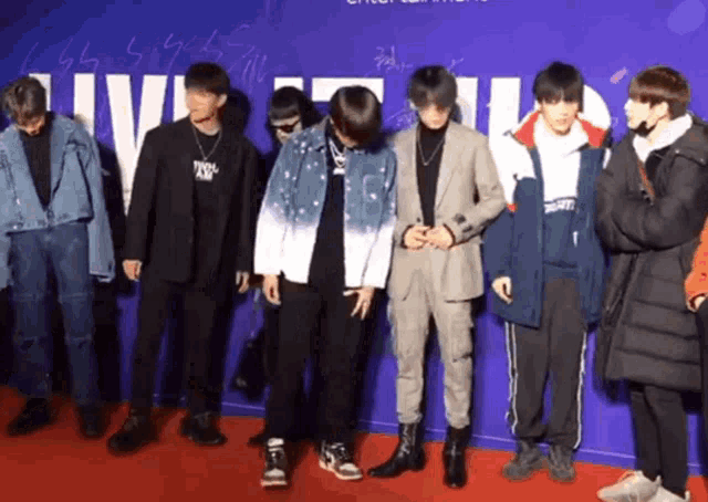 a group of young men are standing on a red carpet in front of a wall that says ' ui ' on it