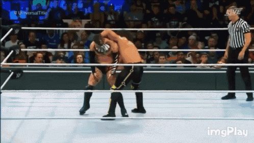 two wrestlers are wrestling in a ring with a referee watching .