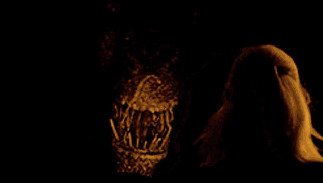 a close up of a monster 's mouth with a woman behind it