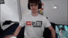 a man wearing headphones and a diesel t-shirt is sitting on a couch .