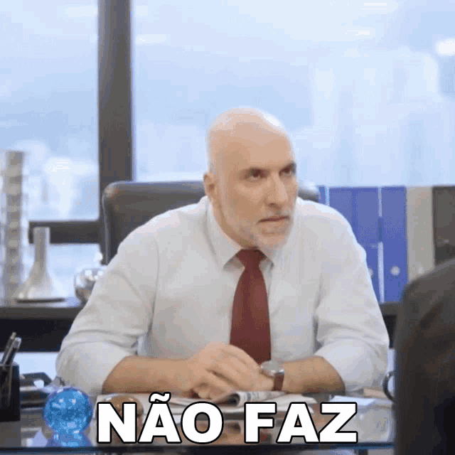 a man sitting at a desk with the words nao faz written on the bottom