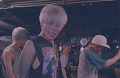 a group of young men are standing in a room . one of the men is wearing a guns n roses shirt .