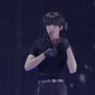 a man is singing into a microphone while wearing gloves .