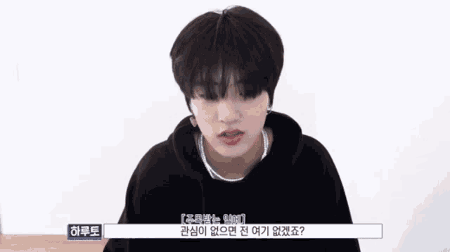 a young man in a black hoodie is talking to someone in a foreign language .
