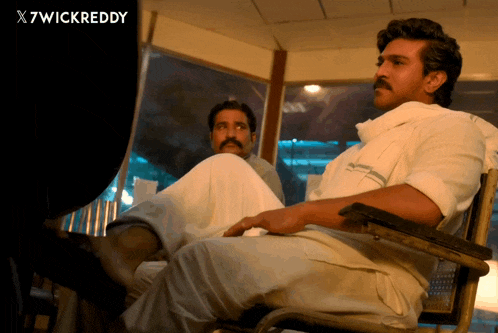 a man with a mustache sits in a chair next to another man with a x7wickreddy watermark