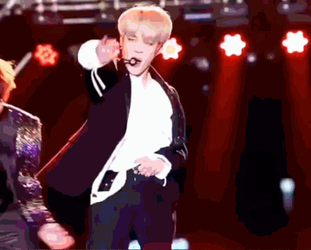 a man in a suit and white shirt is dancing on a stage with a microphone in his mouth .