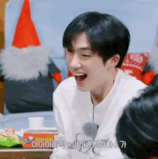 a young man is laughing with his mouth wide open in front of a santa hat